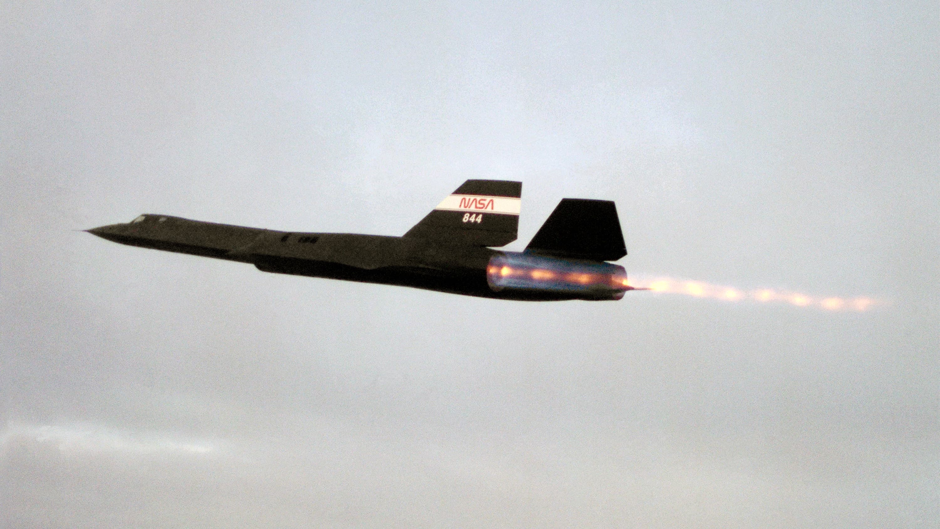 An SR-71 crossing a twilight sky with both afterburners lit